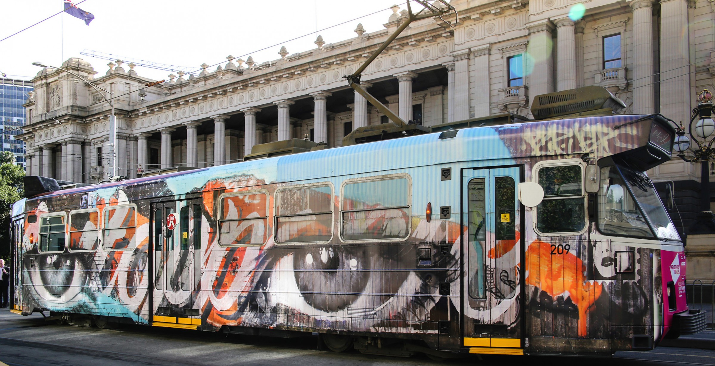 A tram painted with a pair of eyes and colourful accents