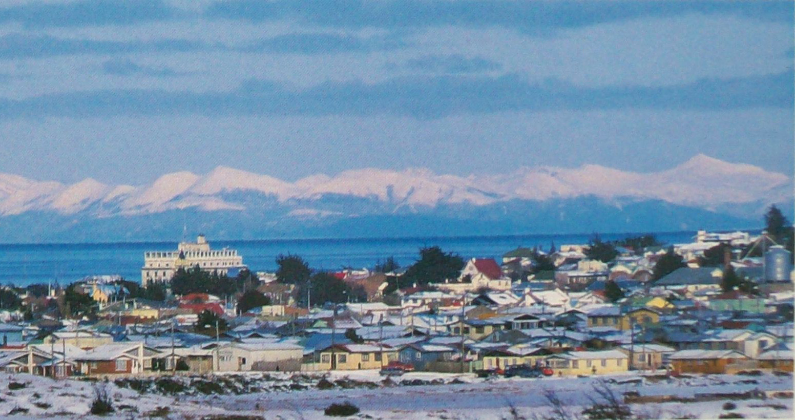 A view over the snowy rooftops of Punta Arenas, Chile, with mountains in the background
