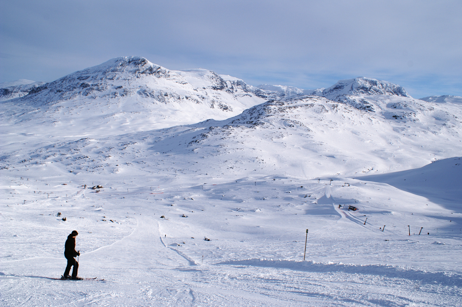 A skier stands at the top of a wide slope in Riksgränsen