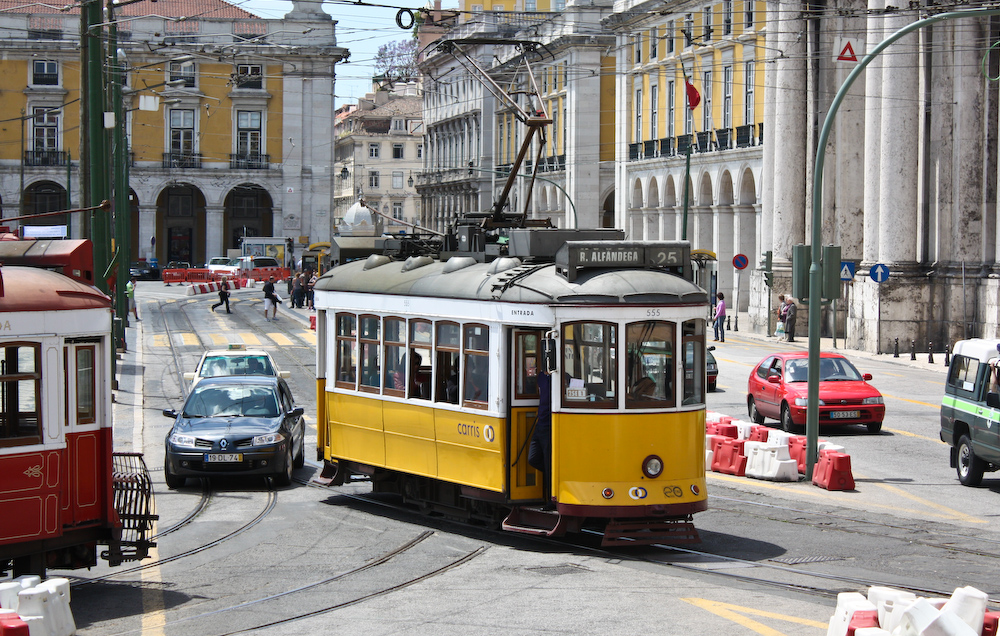 A vintage yellow and white tram rides through Lisbo