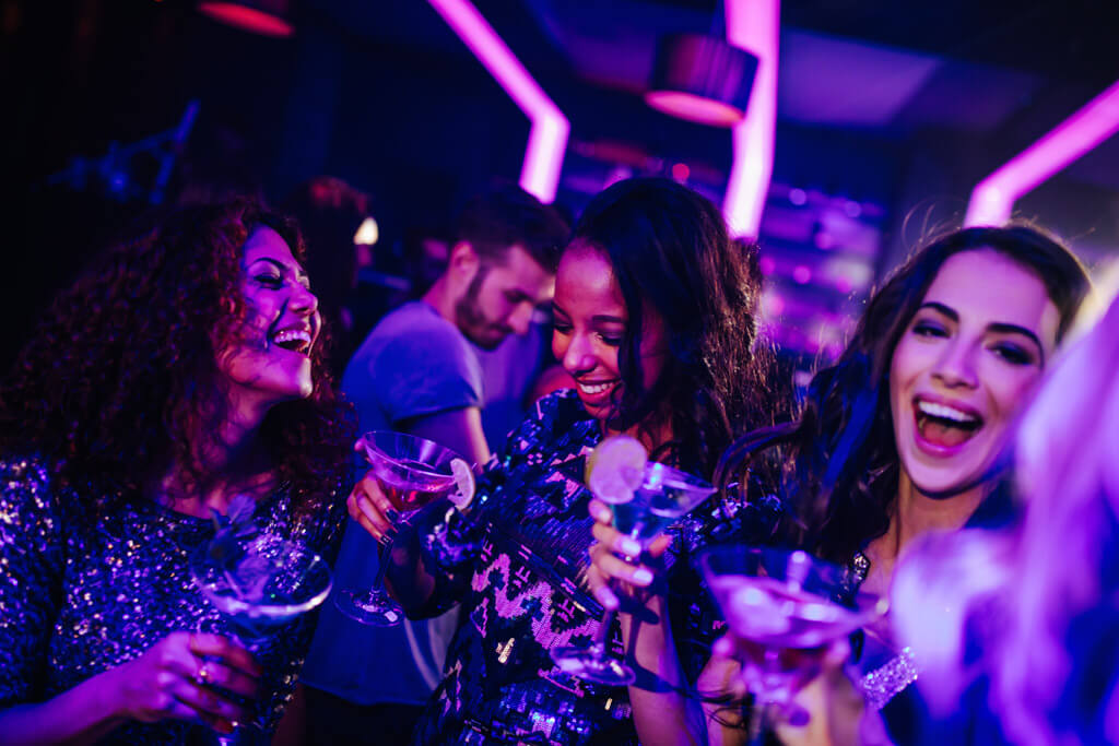 Happy young women enjoying cocktail in night club party