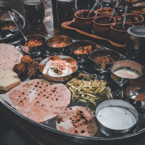 A steel plate with tiny bowls, as well as eating a meal from it.